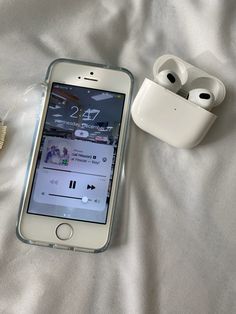 an iphone and ear buds laying on a bed