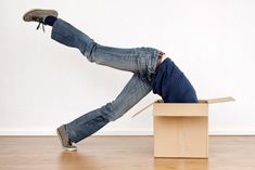 a man laying on top of a cardboard box with his feet in the air,