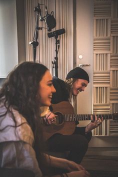 two people sitting on the floor playing guitars