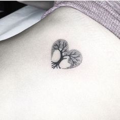 a small tree tattoo on the back of a woman's left side ribcage