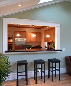 a living room with three stools and a kitchen in the backround behind it