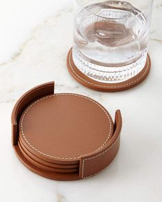 a set of coasters with stitching on them and a glass in the background