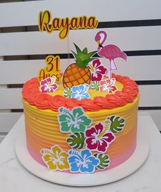 a colorful cake with pineapples and flamingos on top is sitting on a table