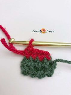 the crochet hook has been hooked up to an object that is red and green