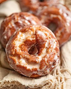 three glazed donuts sitting on top of a cloth