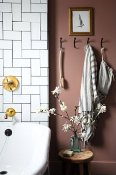 a white bath tub sitting next to a wall mounted shower faucet with flowers in it