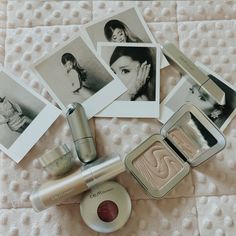 an assortment of beauty products are laying on a white blanket with photos and photographs surrounding them