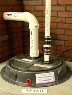 a large white pipe on top of a machine in front of a red brick wall