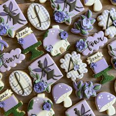 decorated cookies with purple and white designs are arranged on a wooden surface, including the letter d