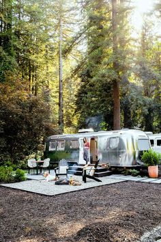 an old camper parked in the middle of a forest next to a picnic table