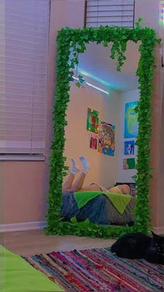 a person laying down in front of a mirror covered in green vines and ivys