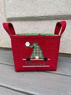 a small red bag with a green and white dog on it's front pocket