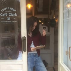 a woman standing in front of a coffee shop holding a plate