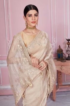 Flaunt your elegant style on festive occasions in this stunning beige embroidered tissue silk saree. It comes with a matching blouse piece. Disclaimer: The shown stitched blouse on the model is for display purpose only. The saree comes with a matching blouse piece and finished with fall and piko. Gold Blouse Piece With Intricate Embroidery In Tissue Silk, Cream Saree With Intricate Embroidery For Festivals, Gold Tissue Silk Blouse Piece With Intricate Embroidery, Beige Zari Work Pre-draped Saree For Wedding, Beige Pre-draped Saree With Zari Work For Wedding, Festive Beige Blouse Piece With Resham Embroidery, Festive Beige Blouse With Resham Embroidery, Cream Embroidered Raw Silk Saree, Festive Beige Blouse Piece With Traditional Drape