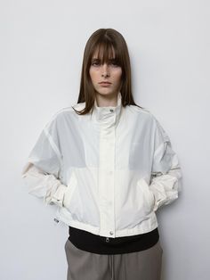 This product is a contemporary windbreaker that combines functionality with fashion, featuring a high neck and elastic cuffs for protection against the elements. The jacket's translucent material and spacious design not only provide practicality but also make it a statement piece for layering. It's an ideal addition for those looking for a blend of style and comfort in their outdoor wear. - The windbreaker includes a zippered front for easy closure and a customizable neckline.- Elasticated cuffs and an adjustable hem ensure a snug fit that keeps the wind out.- It's constructed with lightweight, water-resistant fabric, making it suitable for unpredictable weather.- The jacket's translucent appearance allows for creative styling with various outfits underneath. Techwear Nylon Windbreaker With Ribbed Cuffs, White Techwear Windbreaker For Spring, White Nylon Windbreaker With Reflective Details, White Functional Windbreaker With Reflective Details, White Windbreaker With Ribbed Cuffs For Fall, White Techwear Track Jacket For Spring, Functional Nylon Track Jacket With Ribbed Cuffs, Fall Nylon Windbreaker With Ribbed Cuffs, Athleisure Nylon Windbreaker With Ribbed Cuffs