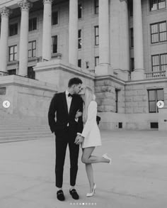 a man and woman standing in front of a large building with columns on each side