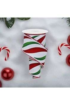 a red and green striped cup sitting on top of a white table next to candy canes