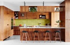 an open kitchen with bar stools and green tile backsplash, surrounded by wooden cabinets