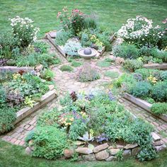 a garden with lots of flowers and plants around it in the middle of a yard