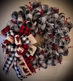 a christmas wreath with red and black plaid bows on the front door, hanging from a wall