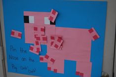 a bulletin board with pink paper cut out of the shape of a pig and words pin the nose on the pig