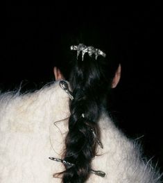 the back of a woman's head with hair pins in her hair and an animal fur coat