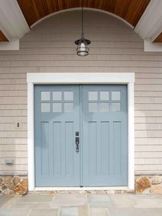 two blue doors are on the side of a house with white trim and wood ceiling