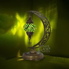 a green lamp sitting on top of a metal stand in front of a green wall