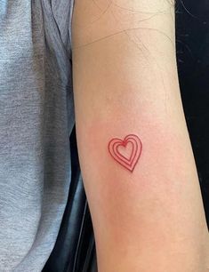 a small heart tattoo on the arm