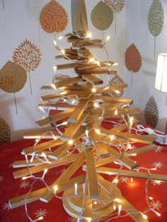 a christmas tree made out of wooden strips with lights around it on a red blanket