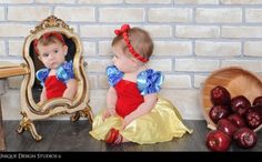 two babies dressed up as snow white and red sitting in front of a mirror