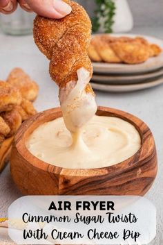 an air fryer cinnamon sugar twists with cream cheese dip is being lifted from a wooden bowl