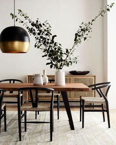 a dining room table with chairs and vases on it