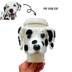 a hand holding a coffee cup with a dalmatian dog on it's face