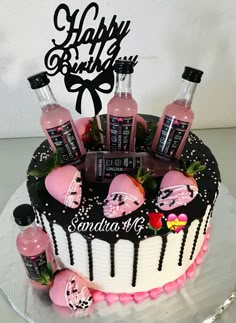 a birthday cake decorated with pink and black frosting, topped with bottles of booze