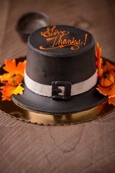 a black and white top hat with orange flowers on the rim, sitting on a wooden table