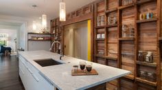 a kitchen with wooden shelving and white counter top next to an open door leading to the living room