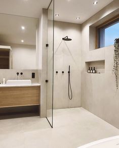 a bathroom with a walk in shower next to a white sink and tub under a window