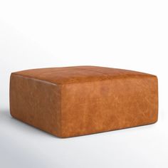 a brown leather ottoman sitting on top of a white floor