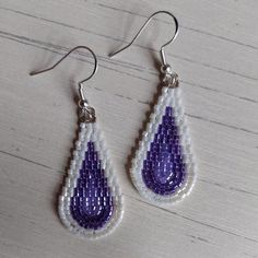 a pair of beaded earrings with purple and white tears