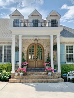 the front entrance to a large house with flowers on the steps