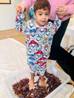 a little boy standing on top of a pile of grapes