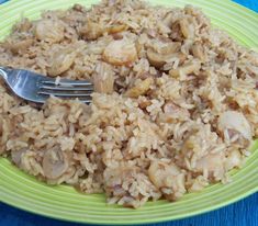 a green plate topped with rice and mushrooms on top of a blue table cloth next to a fork