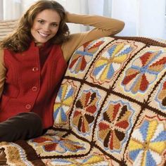 a woman sitting on a couch with a crocheted blanket