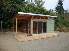 a small wooden building sitting on top of a dirt field next to some green trees