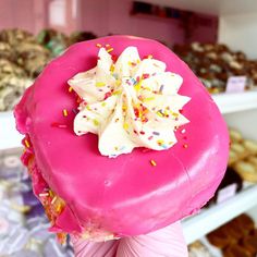 a pink donut with sprinkles and white frosting