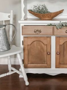 a wooden cabinet with a basket on top of it next to a white chair and table