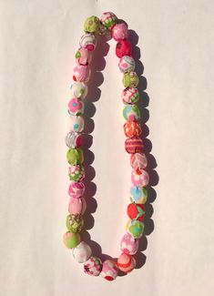 a necklace made out of buttons on a white surface with one bead in the shape of an oar