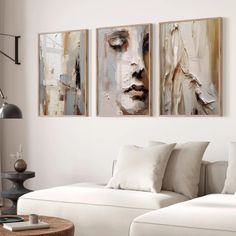 three paintings hang on the wall above a white couch in a living room with pillows