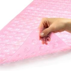 a person's hand is touching the bottom of a pink mattress with water drops on it